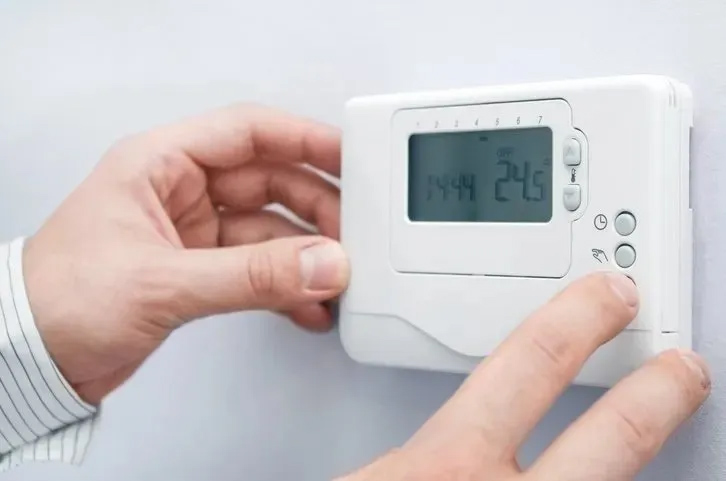 a person's hands setting up a temperature on a white device